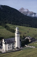 ITALY, Trentino, The Dolomites, The village church of Sesto in the Val di Sesto set below forested