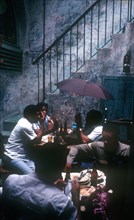 CUBA, Havana, Bodequita del Medio Bar with people sitting at tables in an alley by a stairway and