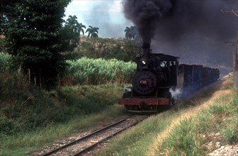 CUBA, Cienfuegos, Sugar train traveling through the country with black smoke pouring from the