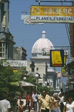 CUBA, Cienfuegos, "Busy street scene with people, hanging shop signs and dome of white building