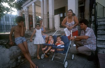 CUBA, Havana, Family standing outside with two babies in a twin pram