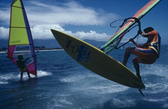 10018445 SPORT Watersports Windsurfing Jamie Hawkins and another surfer on water using boards with brightly coloured sails.