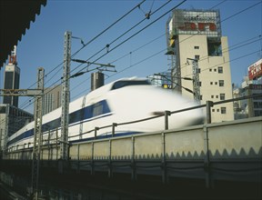 JAPAN, Honshu, Tokyo, Shinkansen Bullet Train speeding along raised railway line in the centre of