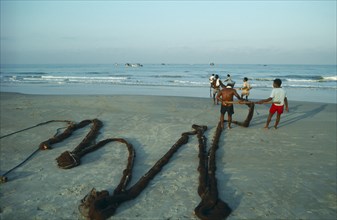 INDIA, Goa, Fishermen hauling nets ashore on Colva beach.
