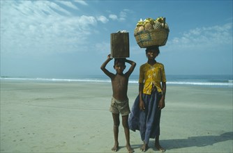 INDIA, Goa, Colva, Boy and girl from Karnataka on beach carrying fruit and drinks to sell to