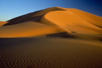 LIBYA , South West  , Achan, Orange desert sand dunes against a clear blue sky