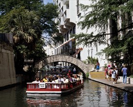 USA, Texas, San Antonio, Pleasure boat passing under a bridge over Paseo del Rio beside the River