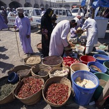 OMAN, Sharqiya, Sanaw, Local people in souk spice stall with spices in baskets and in bins.
