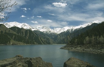 CHINA, Xinjiang, Lake Tianchi, Heavenly Lake with snow capped mountains