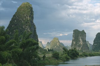 CHINA, Guangxi, Guilin, Yangshuo. View through limestone pinnacles standing by the lake.
