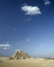 EGYPT, Cairo Area, Giza, Pyramids in desert landscape with shadows cast over sand and Cairo beyond.