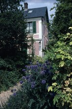 FRANCE, Normandy, Eure , Giverny. Claude Monet’s house with shuttered windows seen through garden