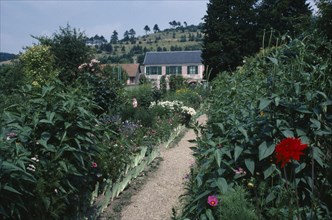 FRANCE, Normandy, Giverny, A path leading through Claude Monet’s garden towards a house.