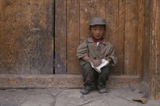 CHINA, Gansu, Xiahe, Young Tibetan boy reading a book