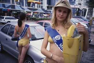 AUSTRALIA, Queensland, Surfers Paradise, Meter maids dressed in gold lame bikini swimwear. The