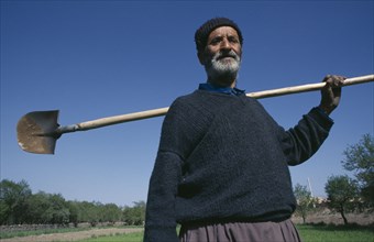 IRAN, Esfahan Province, Portrait of farmer carrying spade over his shoulder