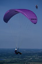 10127601 SPORT  Air Paragliding Paraglider with purple chute and landscape below.