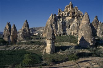 TURKEY, Cappadocia , Goreme, Cave houses carved into large rock surrounded by Fairy chimneys