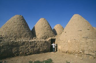 TURKEY, Urfa, Harran  , Beehive mud houses with boy standing at doorway