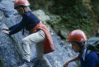 10127733 SPORT  Climbing Woman and child rock climbing wearing red safety helmets in North Wales