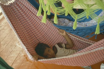 BRAZIL, Amazon, Rio Madeira, Young boy lying in a hammock on a boat