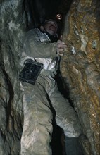 10009982 SPORT Rock Climbing Caving Man climbing in Limestone Area with spotlight on his head.