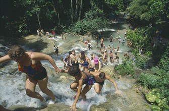 WEST INDIES, Jamaica, Ocho Rios, Tourists helping each other up to the top of Dunns River Falls