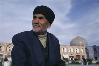 IRAN,  , Esfahan , Portrait of elderly man with Sheikh Lotfallah mosque in background