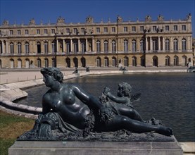 FRANCE, Ile de France, Yvelines, Versailles. Part view of palace with bronze reclined statue of