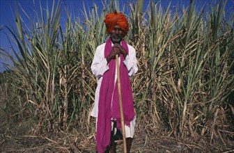 INDIA, Maharashtra, Full length portrait of man wearing pink scarf and red turban.