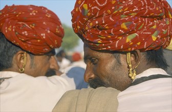 INDIA, Rajasthan, Nagur, Two men wearing turbans and earrings with backs to camera