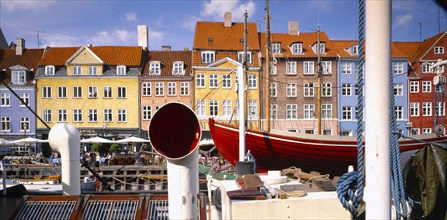 DENMARK, Copenhagen, Nyhavn Canal.  View over boats to pavement cafes and waterside buildings.