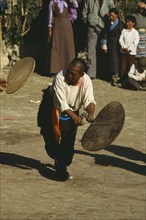 CHINA, Tibet, Dancer beating a hide drum at a festival