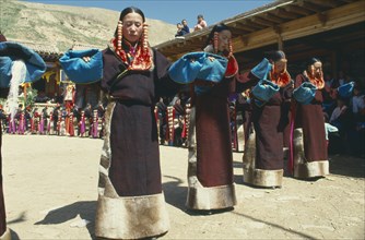 CHINA , Qinghai, Tongren, Line of women dancers in costume at Tibetan festival