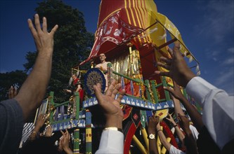 RELIGION, Hare Krishna, View over the reaching hands of a crowd toward brightly decorated cart with