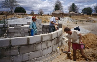 TANZANIA, Work, Men laying building blocks for a water tank in a small village with thatched huts