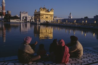 INDIA, Punjab, Amritsar, Golden Temple.  General view with pilgrim group sitting beside sacred pool