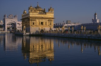 INDIA, Punjab, Amritsar, Golden Temple with pilgrims and visitors on causeway or the Guru’s Bridge