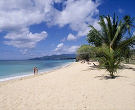 WEST INDIES, Grenada, Magazine Beach, View along quiet sandy beach with a couple standing at the
