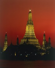 THAILAND, Bangkok, Wat Arun Temple Of The Dawn illuminated at sunset with orange sky and river in