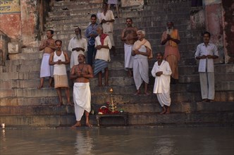 INDIA, Uttar Pradesh, Varanasi, Group worship on the River Ganges.