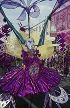 ENGLAND, London, Notting Hill Carnival dancer in a purple costume.