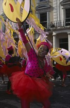 ENGLAND, London, Notting Hill Carnival dancer wearing a pink and red costume