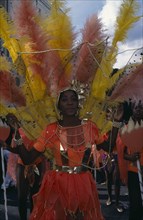 ENGLAND, London, Notting Hill Carnival. Woman in orange costume with orange and yellow feathers and