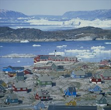 GREENLAND, Denmark, Jakobshaven, View over Ilulissat town with the sea and icebergs beyond coloured