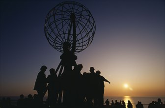 NORWAY, Finnmark, Nordkapp, The North Cape globe sculpture with tourists watching the midnight sun