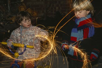 FESTIVALS, Fireworks, Gut Fawkes, Two young children in scarfs and gloves waving sparklers in the