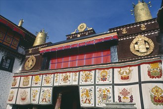 TIBET, Lhasa, Jokhang Temple, Golden Wheel of Dharma on roof of building covered in hanging fabrics