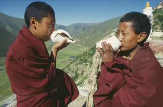 TIBET, Drigung Til Monastery, Two monks calling other monks to prayer by blowing into conch shells