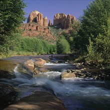 USA, Arizona, Sedona, River cascading over rocks below the mountains and trees